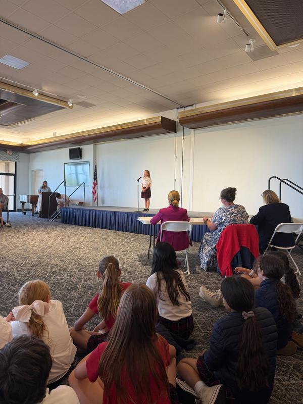 student stands on stage in front of judges reciting a poem