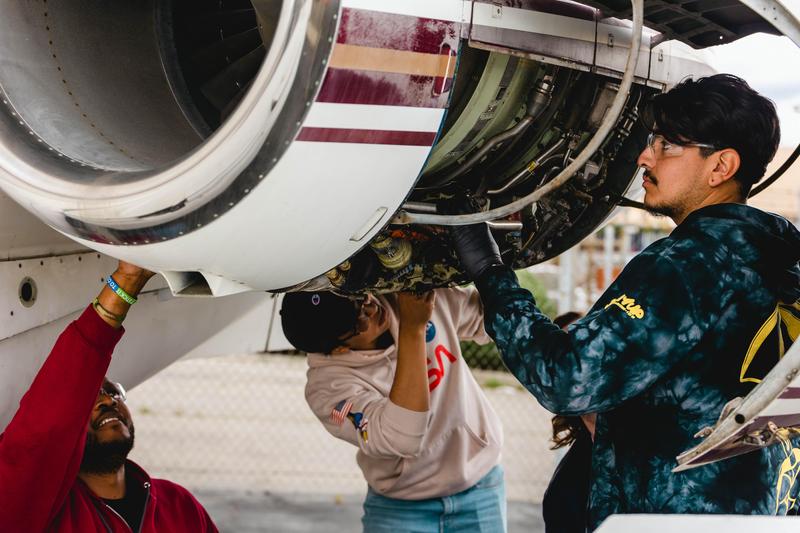 Aviation students working on a jet engine in the shop area.