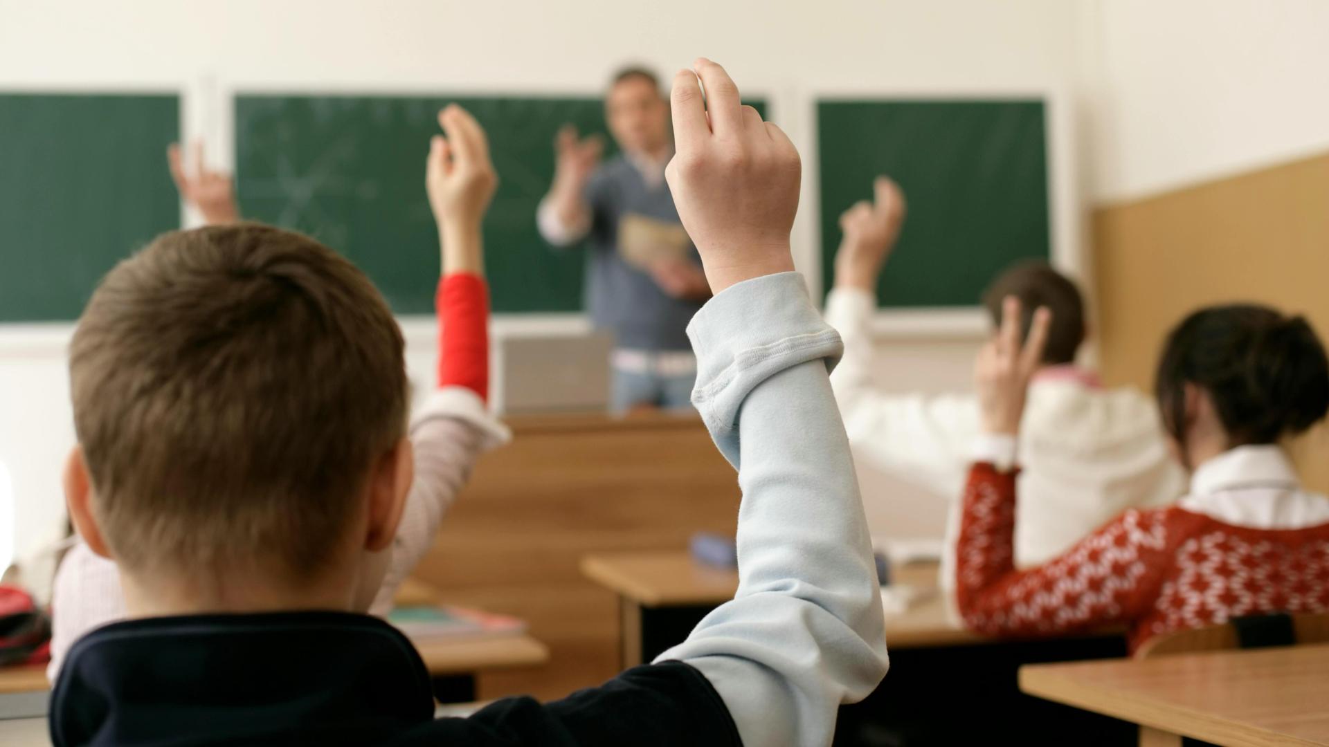 Students with raised hands in a classroom