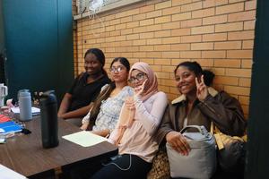 Four girls sitting together at a table in a school setting.