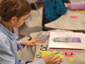 A fourth grade girl focusing on her prefix and shoresh cards.