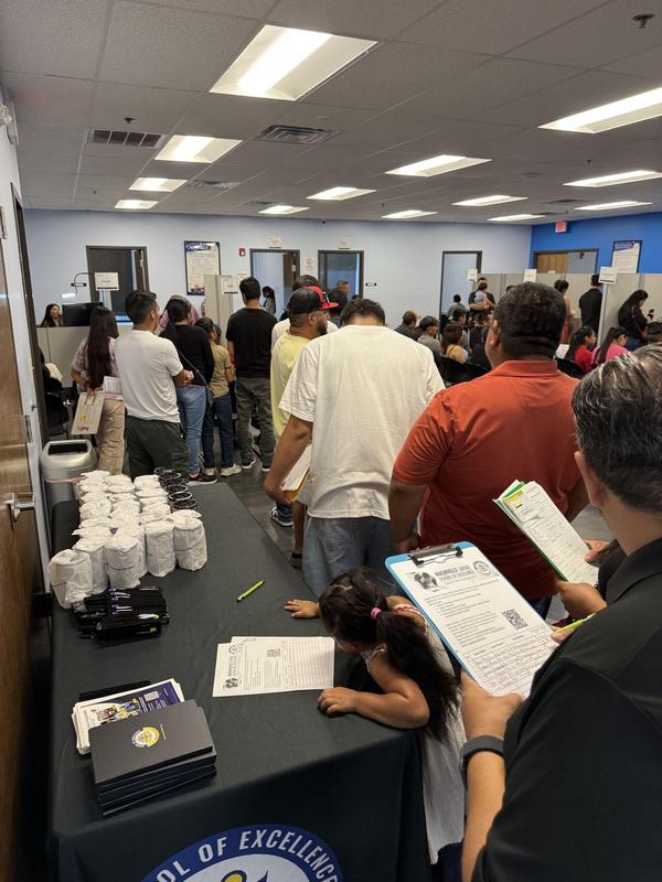 Families visit the Nashville School of Excellence information table at the Guatemalan Consulate, learning about the school and completing parent interest forms.