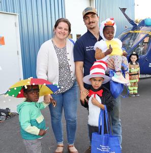 Group of parents and three kids pose outside of hangar