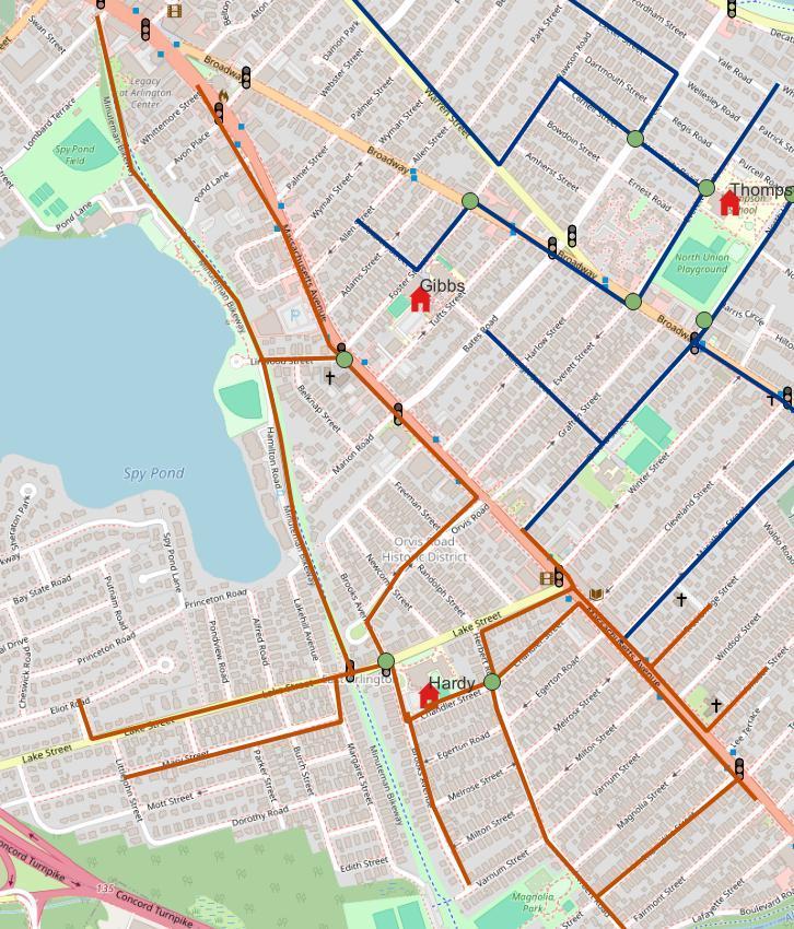 Map of the Hardy School walking route shown in orange. The route runs along Massachusetts Avenue and Broadway from near Spy Pond south to Hardy School on Chandler Street, with additional branches along Lake Street, Egerton Road, and side streets toward Milton and Varnum Streets. Traffic supervisor posts and signalized intersections are marked along the route