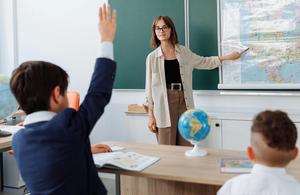 teacher points to map, student raises hand