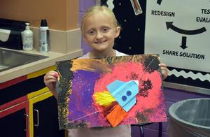 A girl holding a space-themed artwork