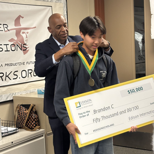 Representative from Edison placing a medal on Brandon Chang