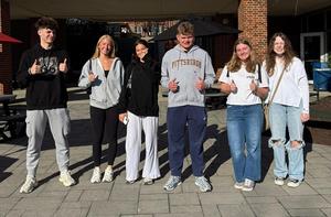 Six students posing together outdoors, all giving thumbs up.