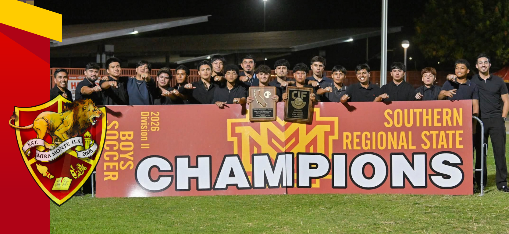 Soccer team posing with championship banner and trophies outdoors.