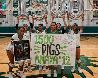Six volleyball players celebrating with a banner and balloons highlighting 1500 digs.