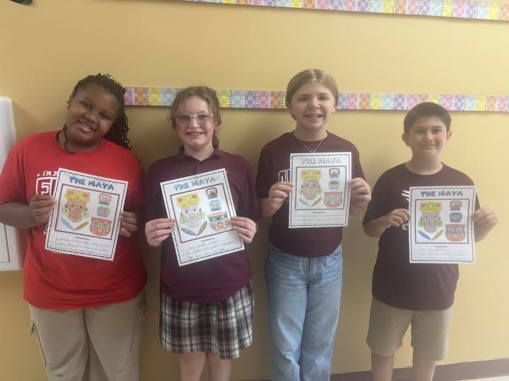 Four 5th-grade students show off their Mesoamerica Day artwork.