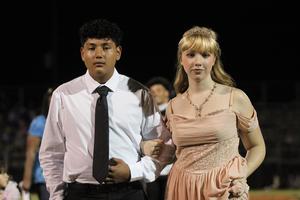 A young man and woman dressed formally walk together.