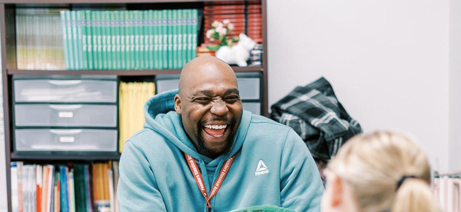 Smiling teacher holds up flash cards for a student