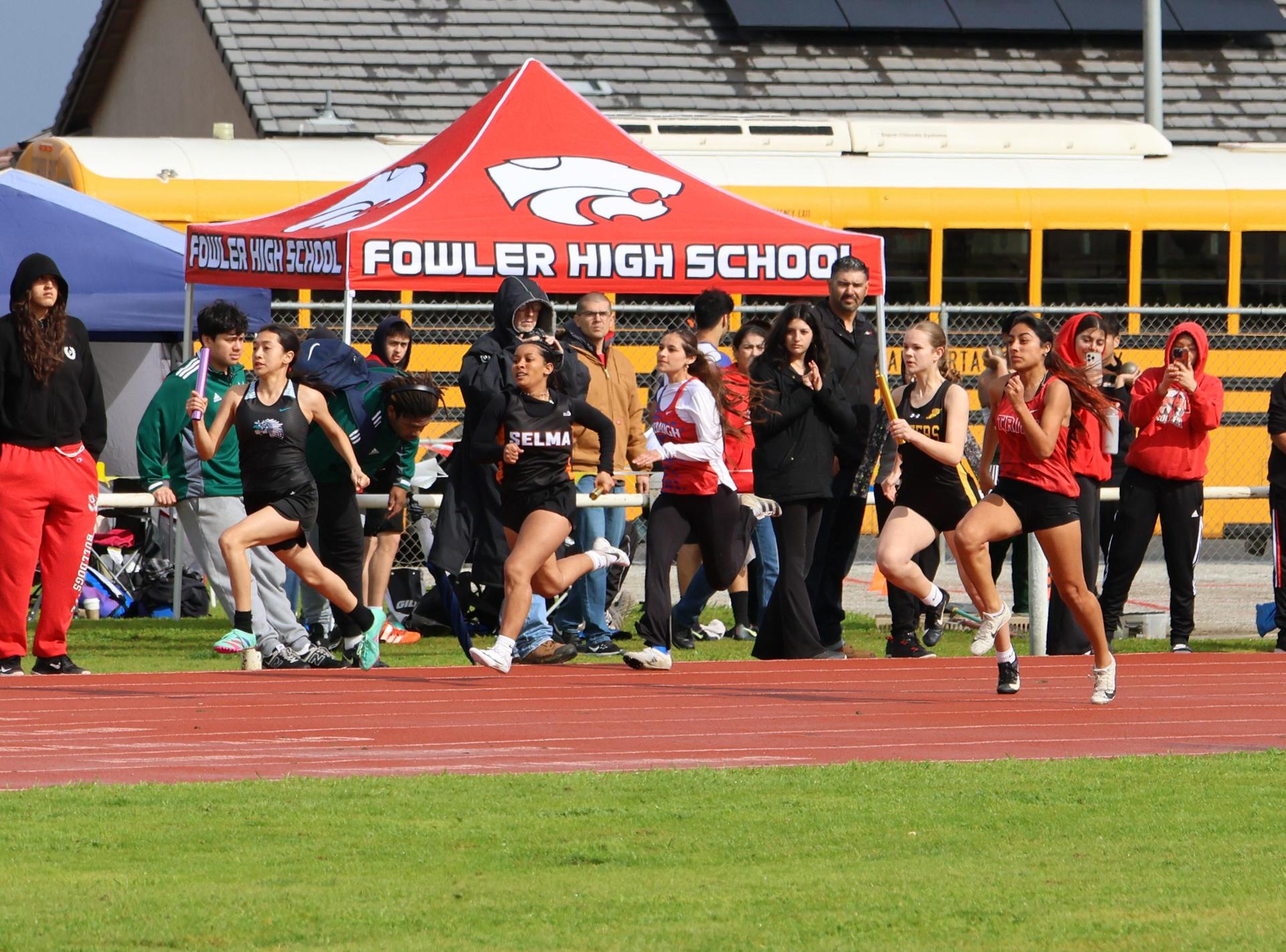 girls running the four by 100 meter relay