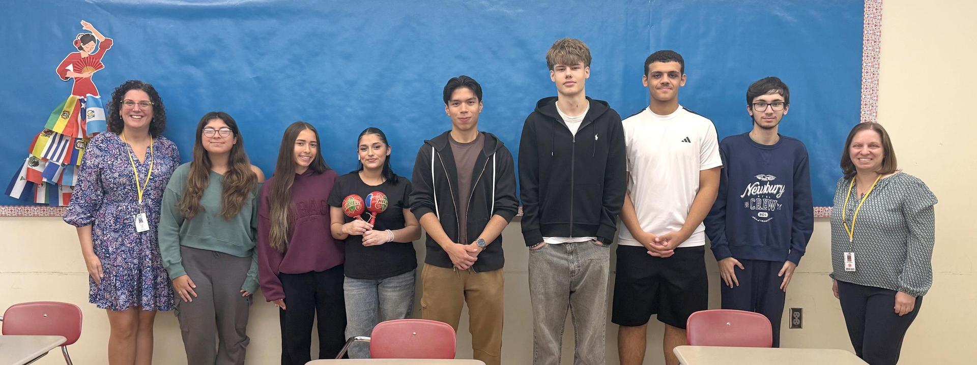 A group of students and teachers standing together in a classroom.