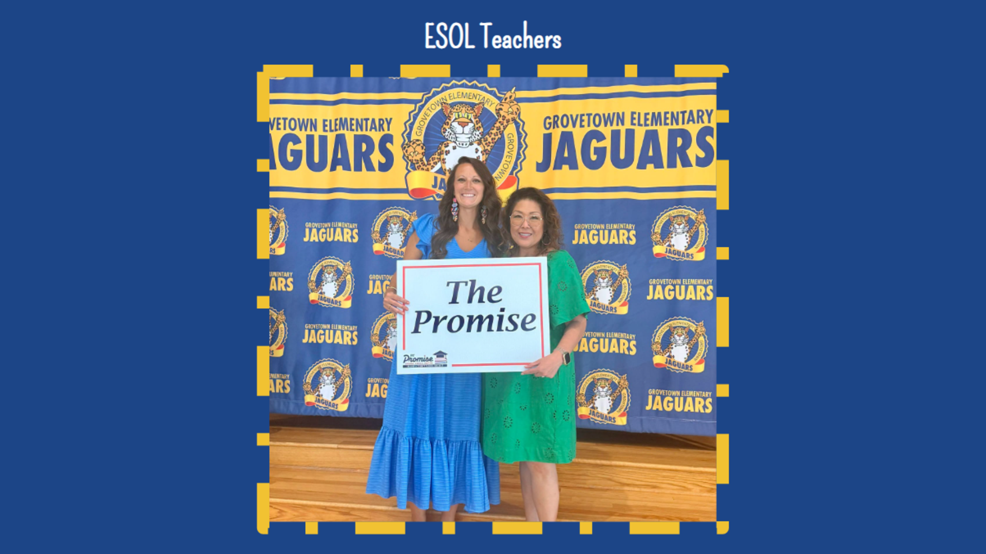 Two women hold a sign reading 'The Promise' in front of a school banner.