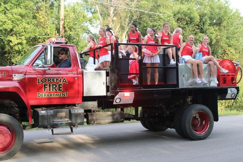 Lorena cheerleaders riding on the back of a red Lorena fire department truck