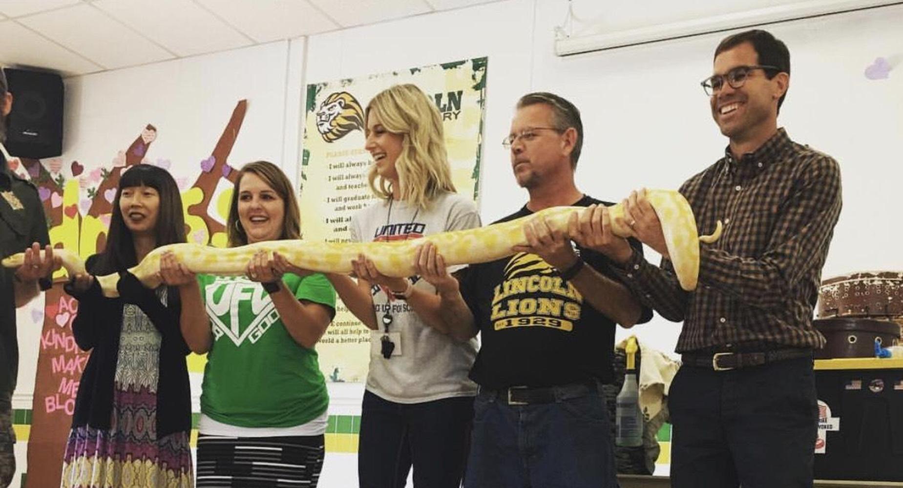 Teachers holding snake at assembly.