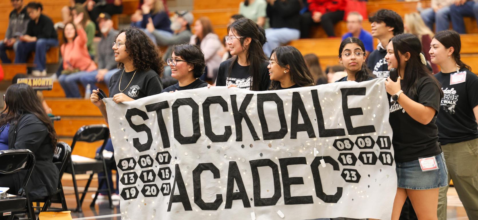 Students holding a banner that reads 'Stockdale Acaddec' at a school event.