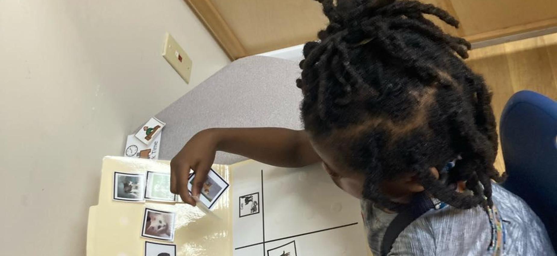 Child placing images on a board during a learning activity.