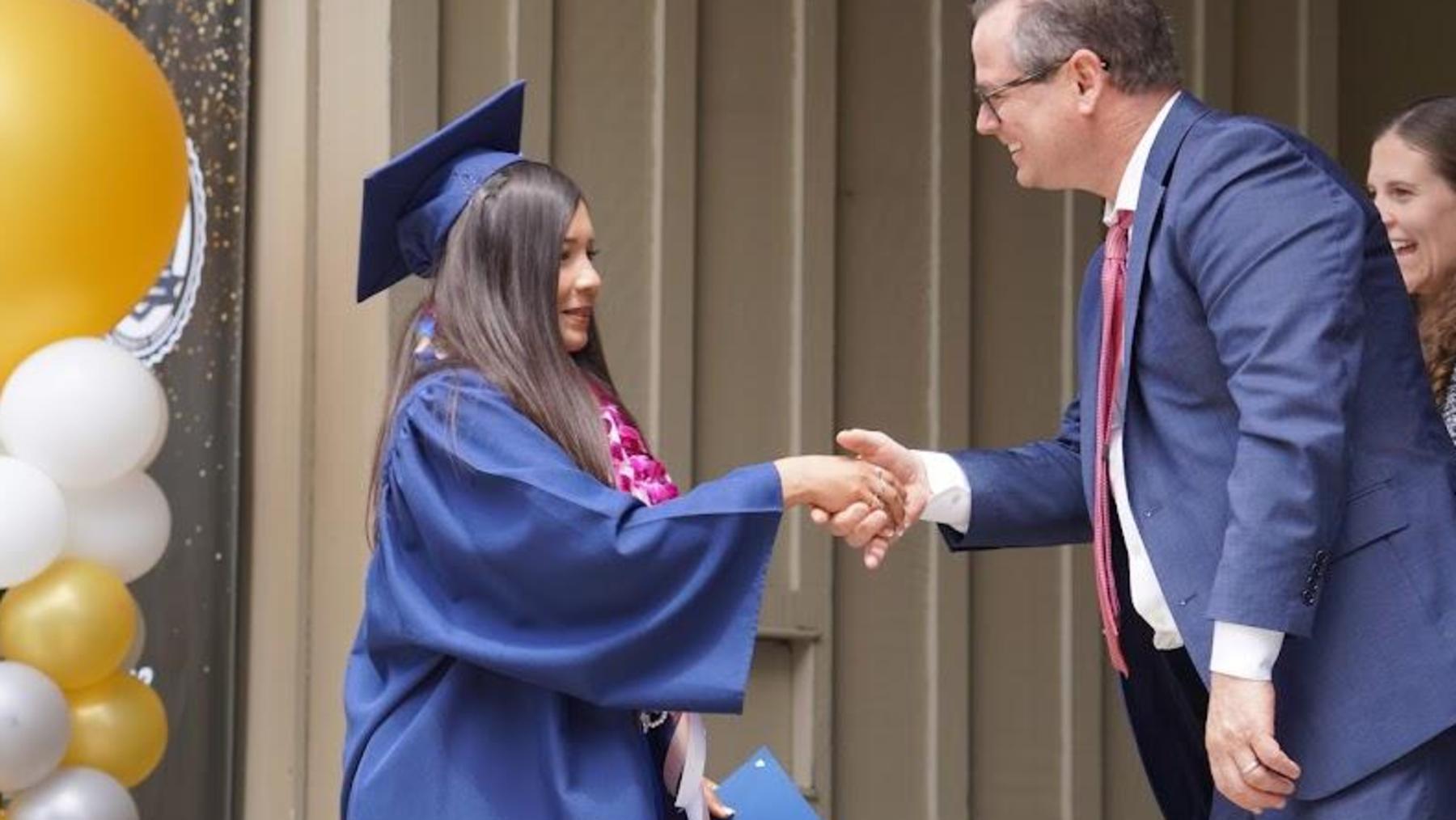 8th grade promoting student shakes hands during promotion ceremony with Superintendent PK Diffenbaugh