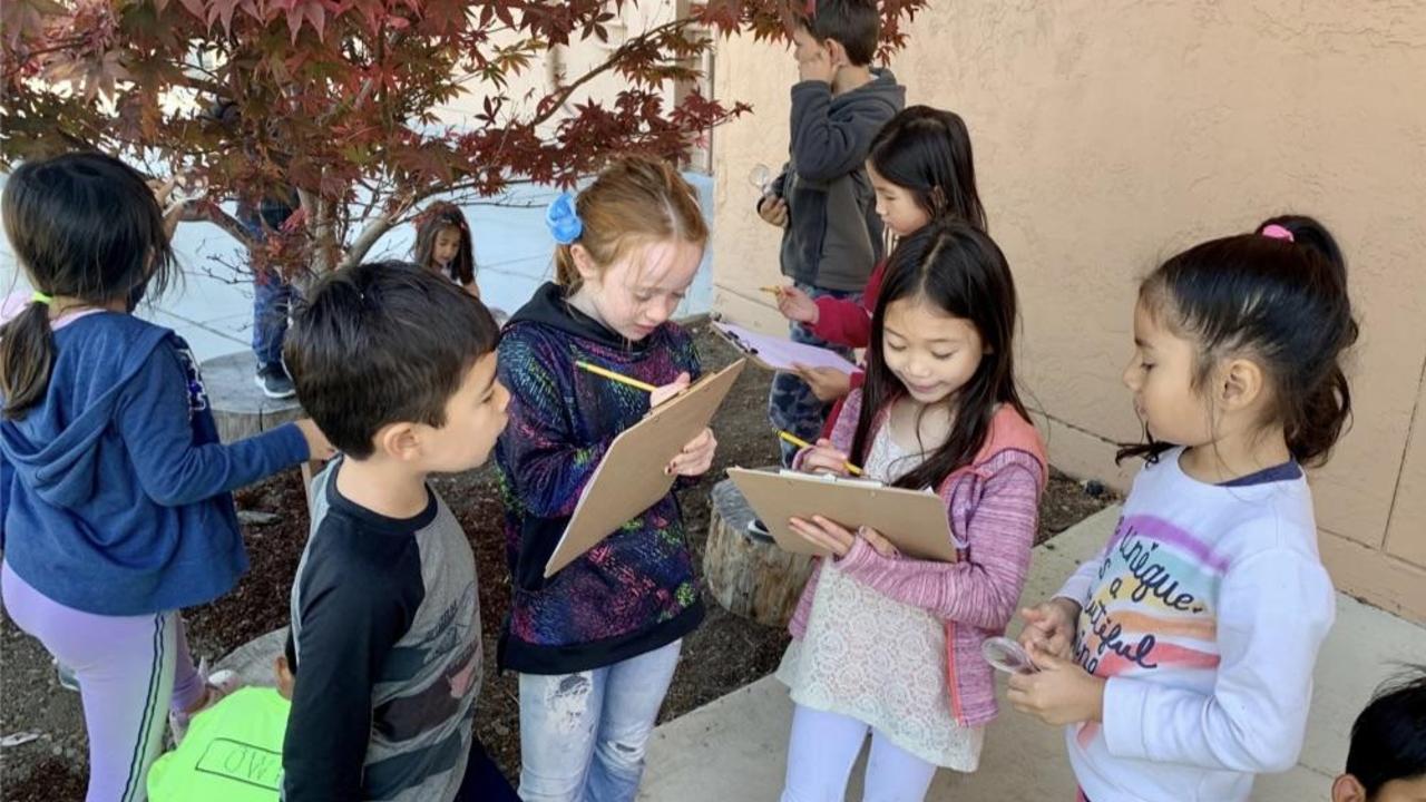 Group of children outdoors engaging in a creative activity.