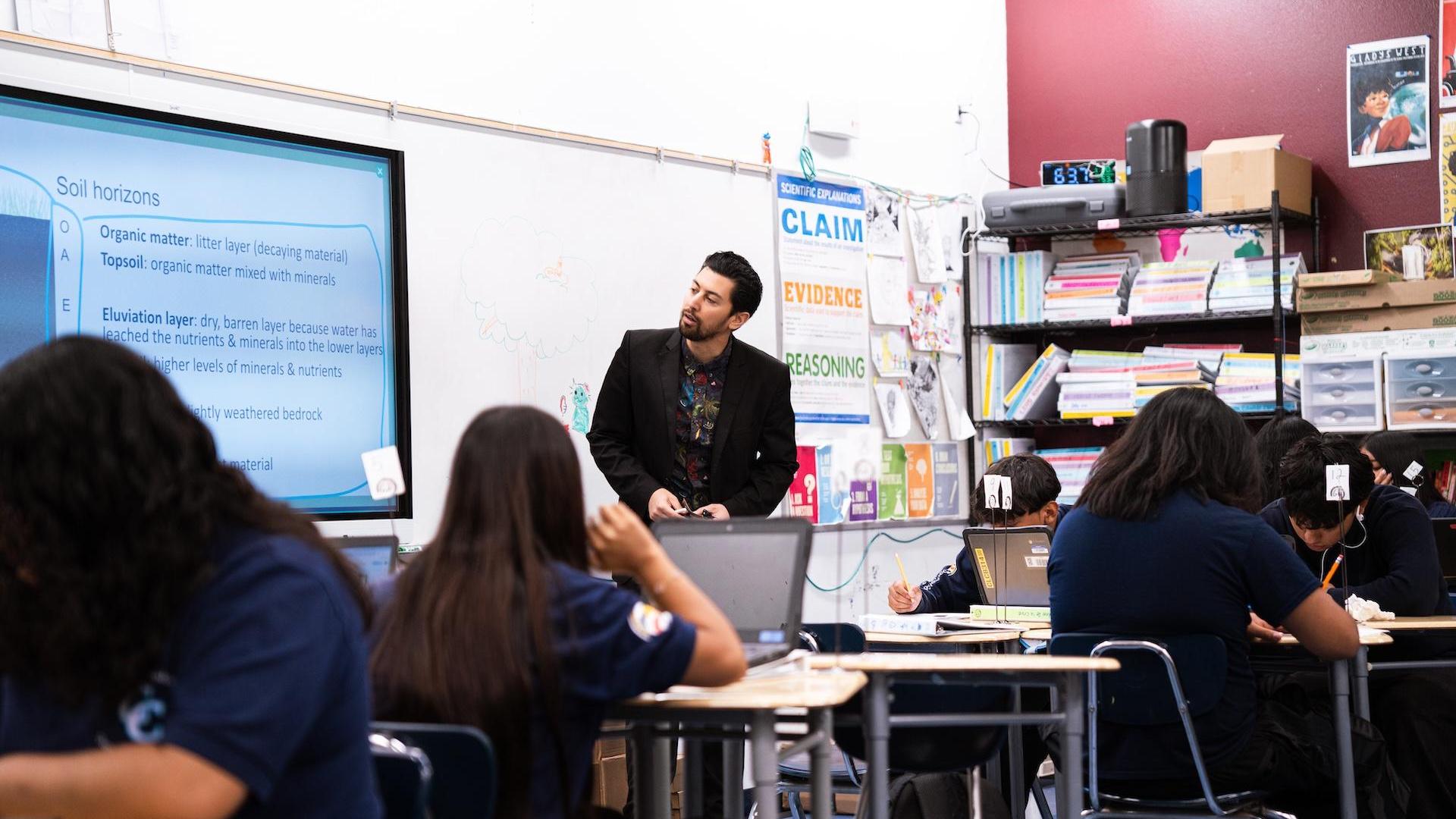 Teacher presenting a lesson on soil horizons to students in a classroom.