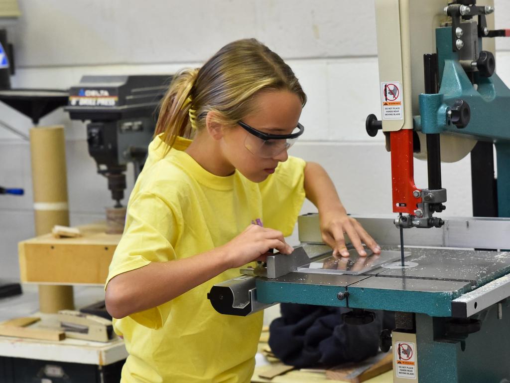 A student using a jigsaw in a classroom.