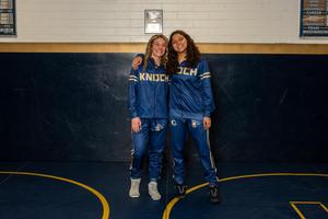 two high school girls dressed in wrestling attire smiling