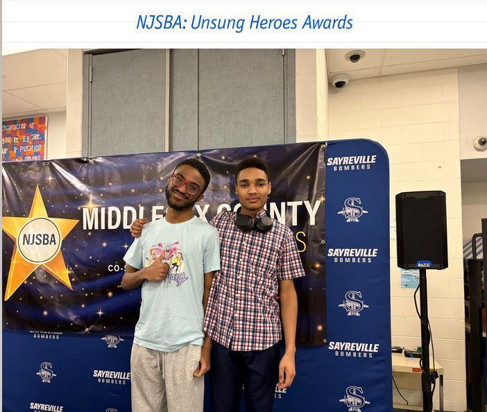 Two boys standing together in front of a sign.