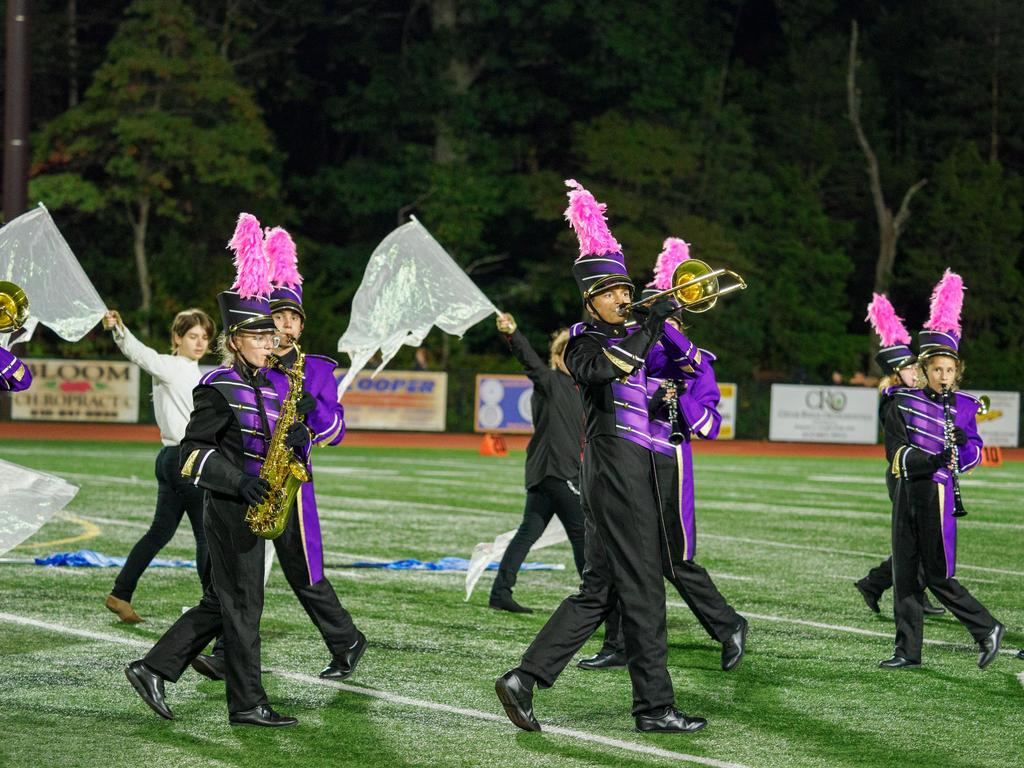 The marching band with flags and brass instruments in the middle of a performance.