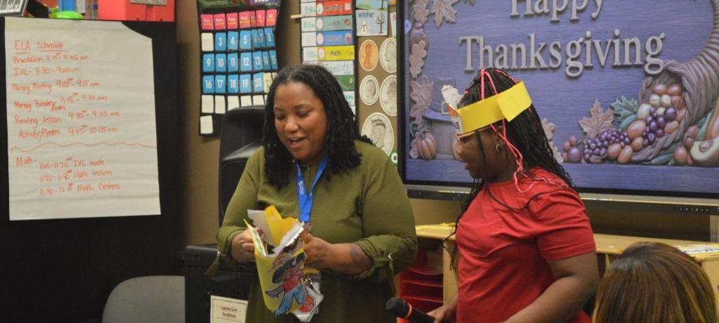 Teacher and student show off Thanksgiving assignment