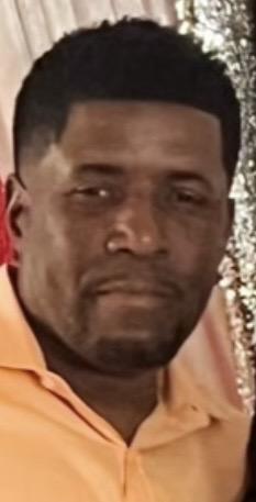 Close-up of a man with short hair wearing a light orange shirt.