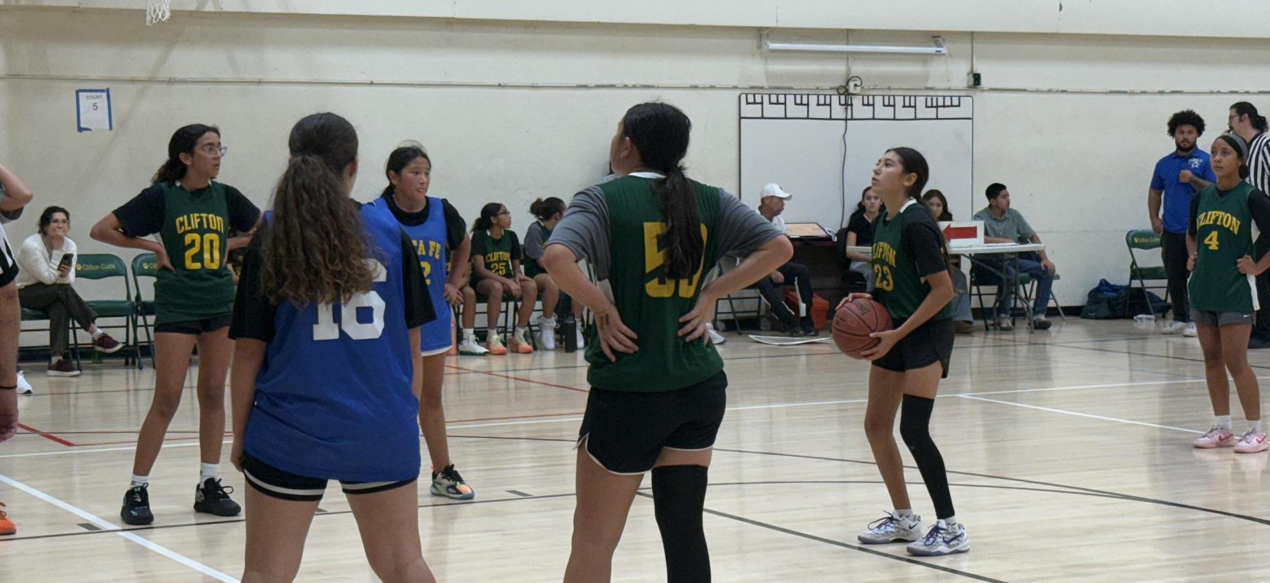Girls basketball players in a gym preparing for a free throw shot.