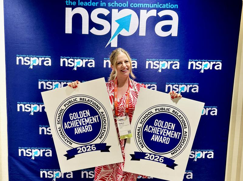 Happy and proud woman stands holding two awards for NSPRA