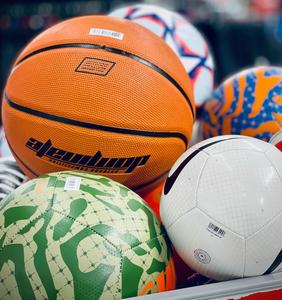 Sports gear such as basketball and soccer balls in a bin