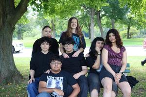 A group of students sit on a bench outside.