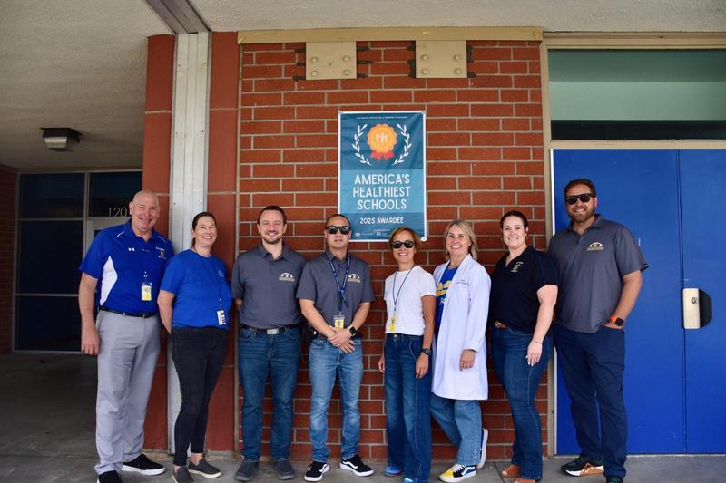 FVHS admin and nurse pose in front of health schools banner