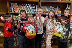 6 students hold books and wildflowers that they planted