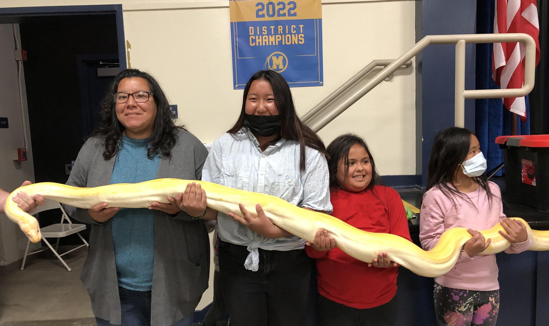 Picture of staff and students holding a large snake