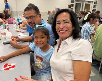 Adults and a girl smiling at a table during an event.