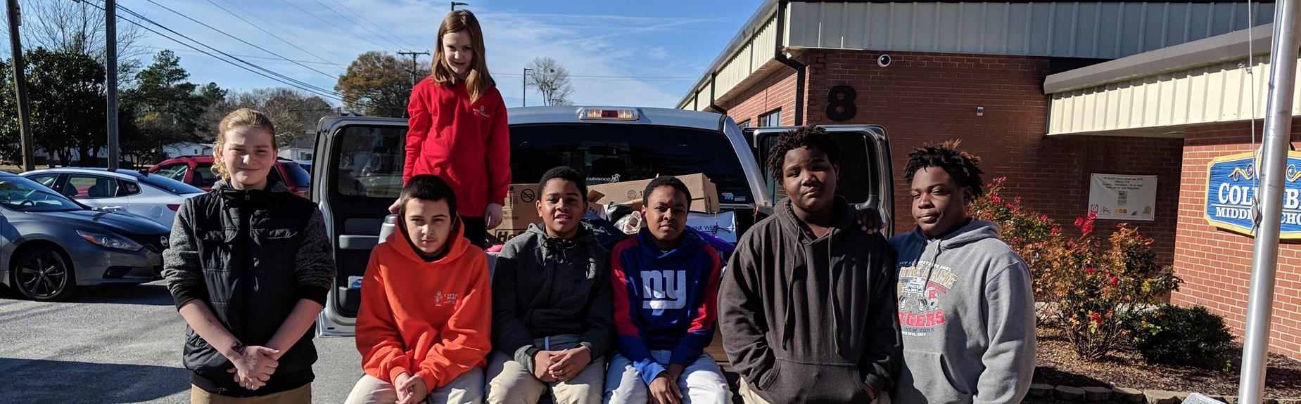 volunteer students sitting in truck bed