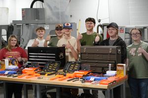 students giving thumbs up behind table of tools
