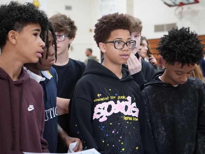 Group of teenage boys looking at something with attentive expressions.