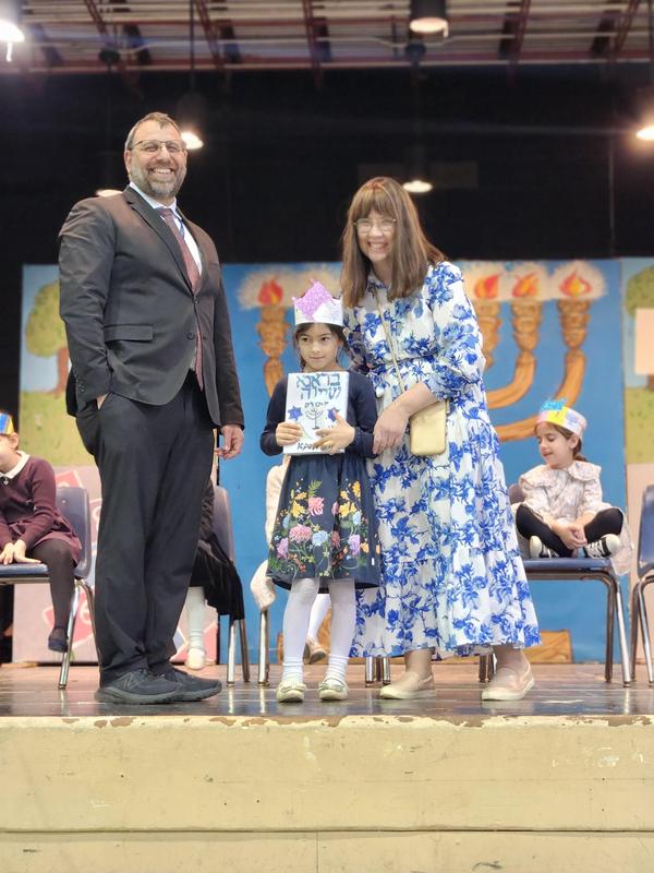 A proud student recieves her chumash.