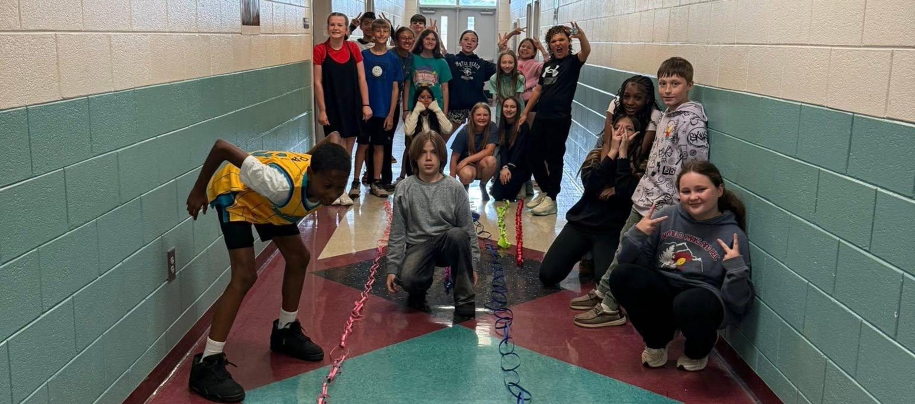 Group of students posing joyfully in a school hallway.