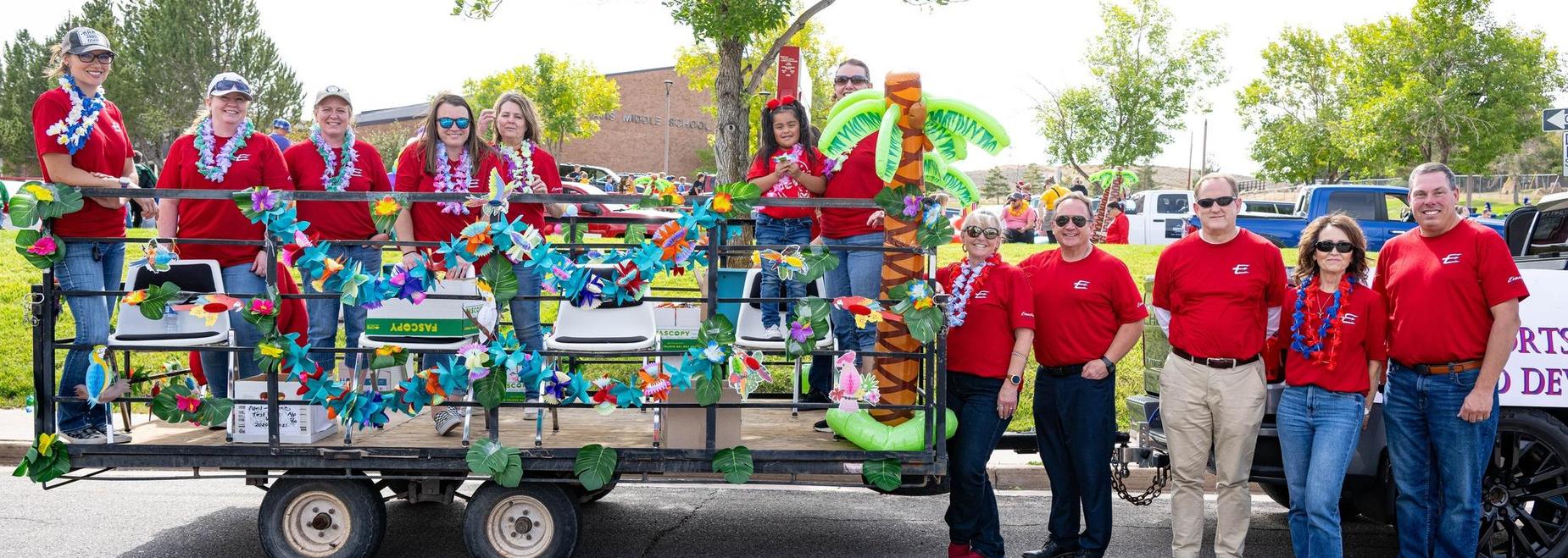 Participants in red shirts adorn a float with tropical decorations and flowers.