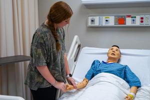 MHS Health Science student taking the blood pressure of a work study dummy doll