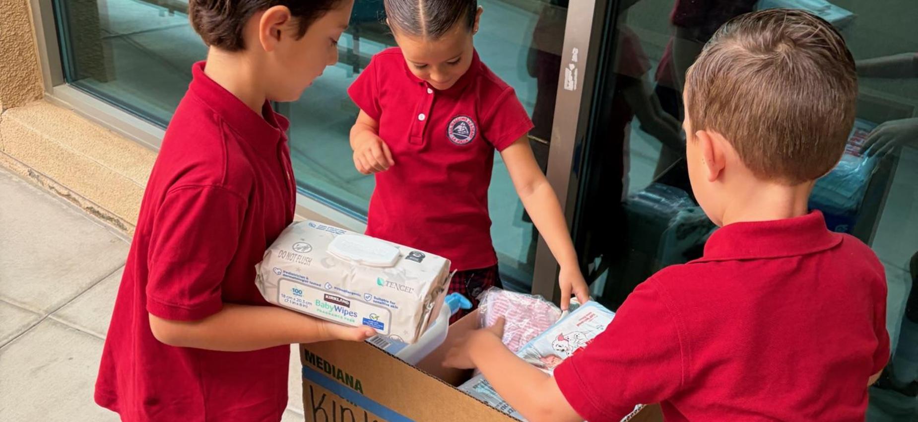 3 students put diapers and wipes into donation box