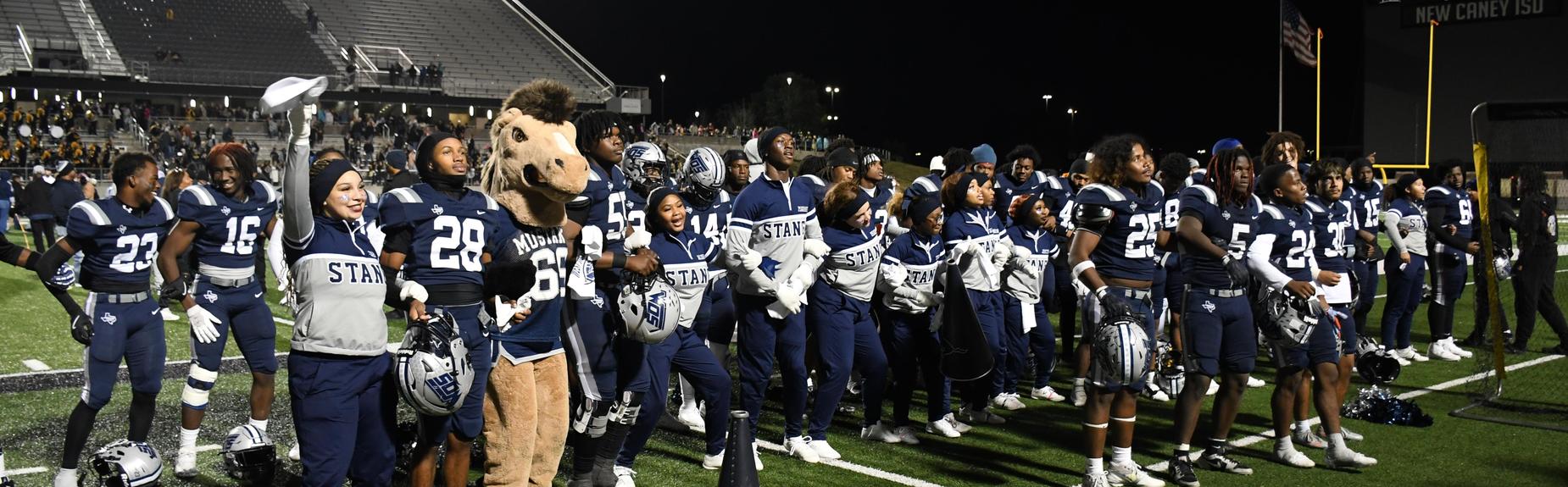 Sports team and mascot celebrating together on the sidelines after a game.
